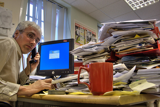 worker with coffee mug and pile of papers