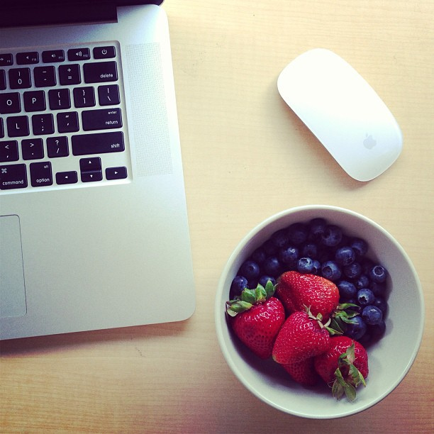 bowl of berries next to laptop