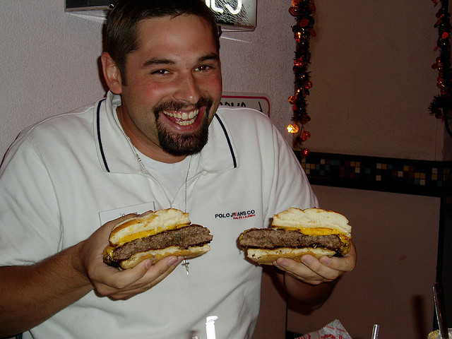 man with cheeseburger cut in half