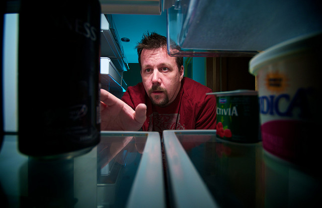 man reaching into fridge