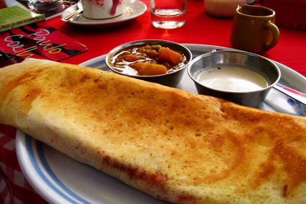 The best Indian food, a masala dosa, sits on a plate.