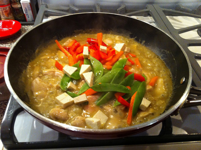 A green curry dish being cooked.